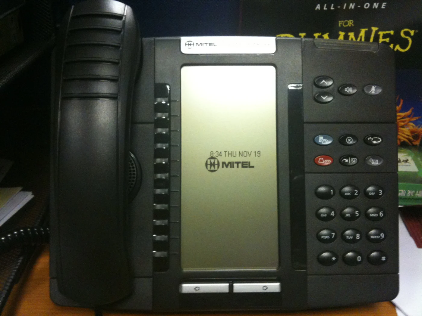 Black Mitel office telephone sitting on a desk.